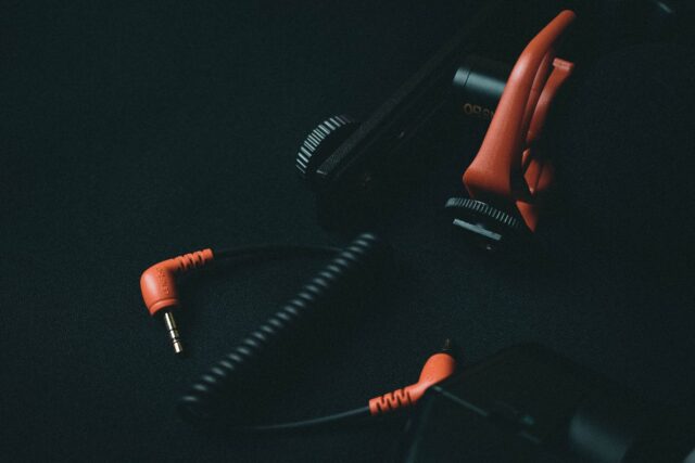 Cabluri audio strânse în colac, cu conectori XLR, jack și RCA așezați pe o suprafață întunecată