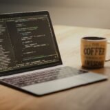 Laptop pe un birou cu un editor de cod deschis și un terminal în care se lucrează cu Git