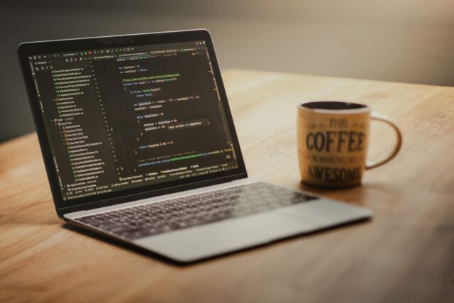 Laptop pe un birou cu un editor de cod deschis și un terminal în care se lucrează cu Git